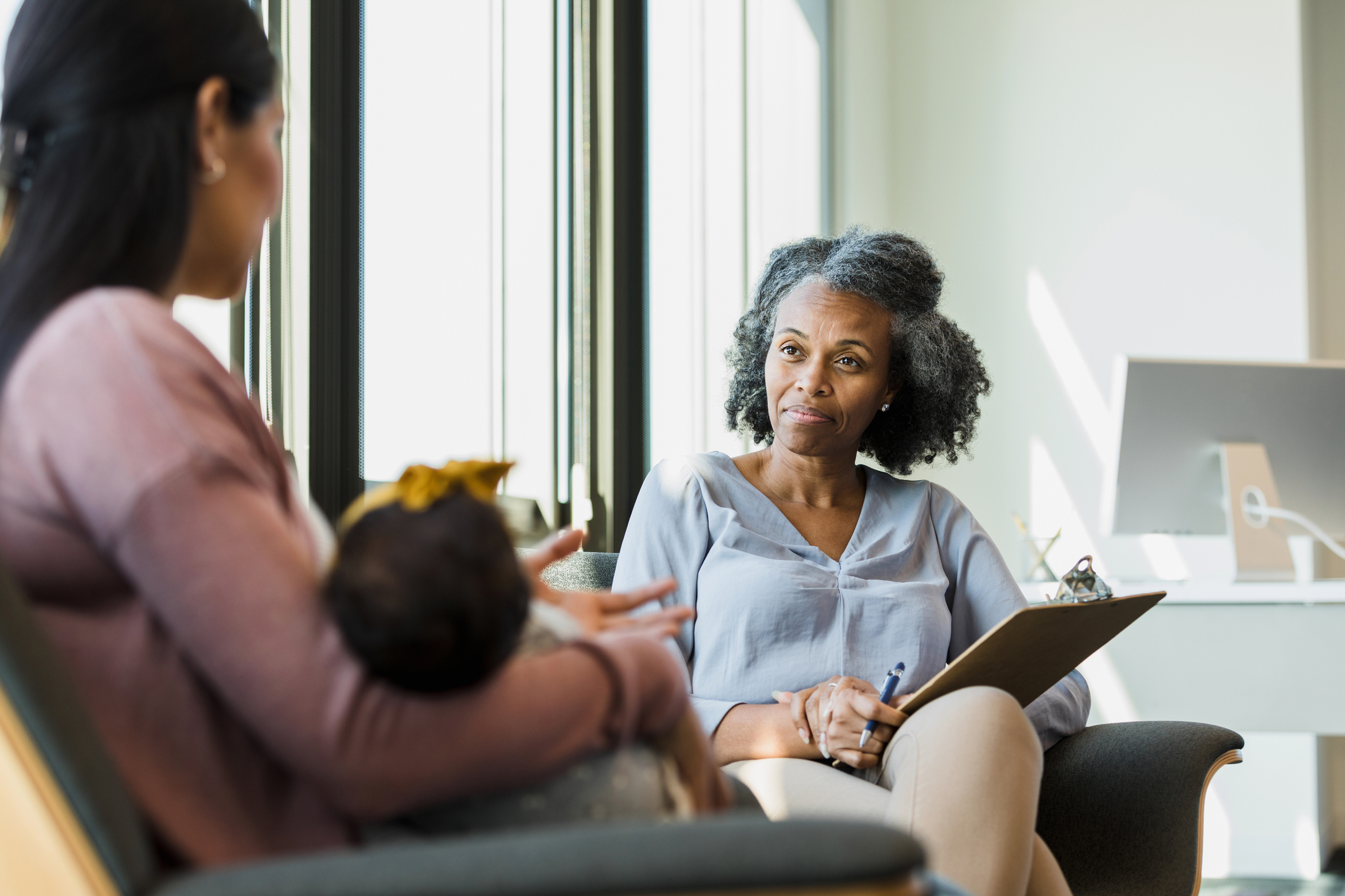 Mother holding a baby while talking with a therapist