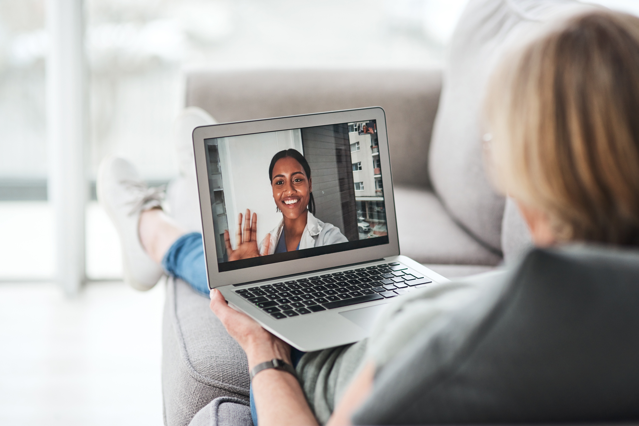 Person sitting on couch with laptop having a virtual appointment with a provider