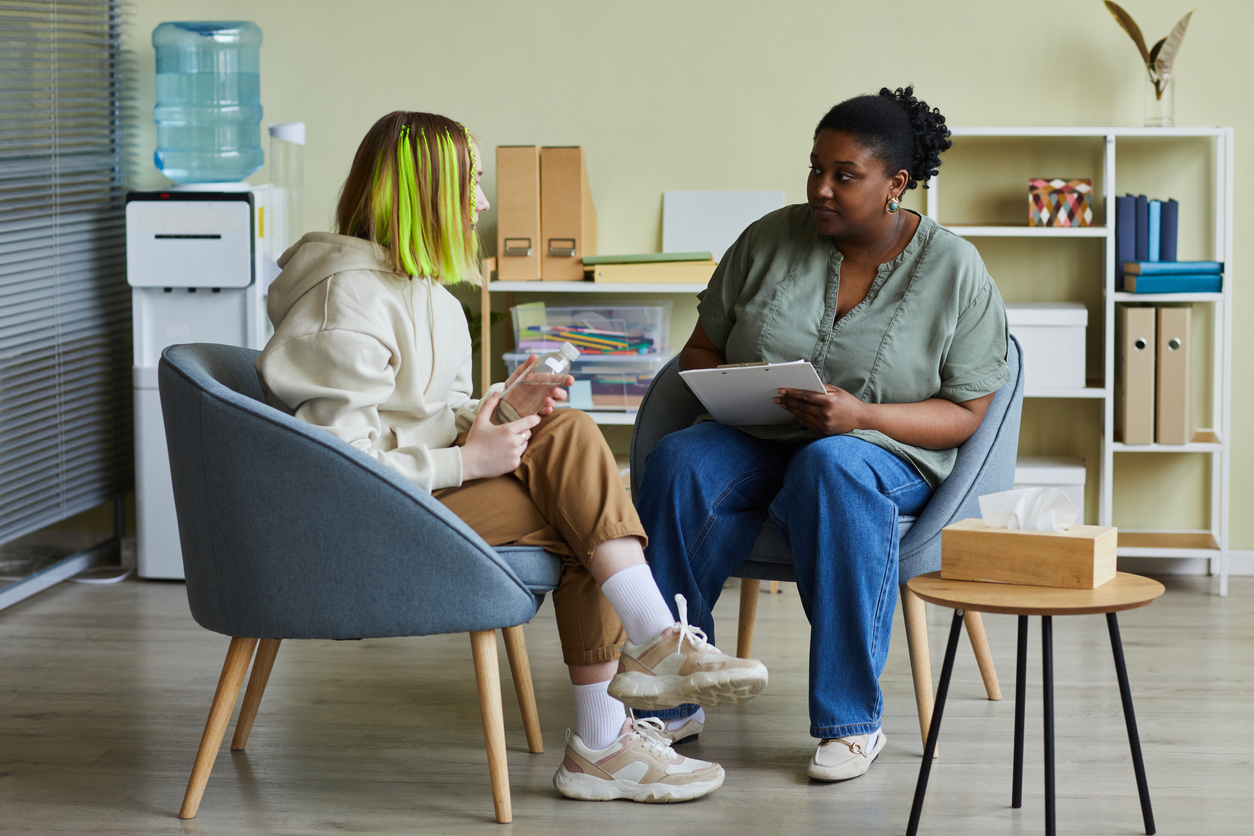 Behavioral health professional sitting and talking with a teenager