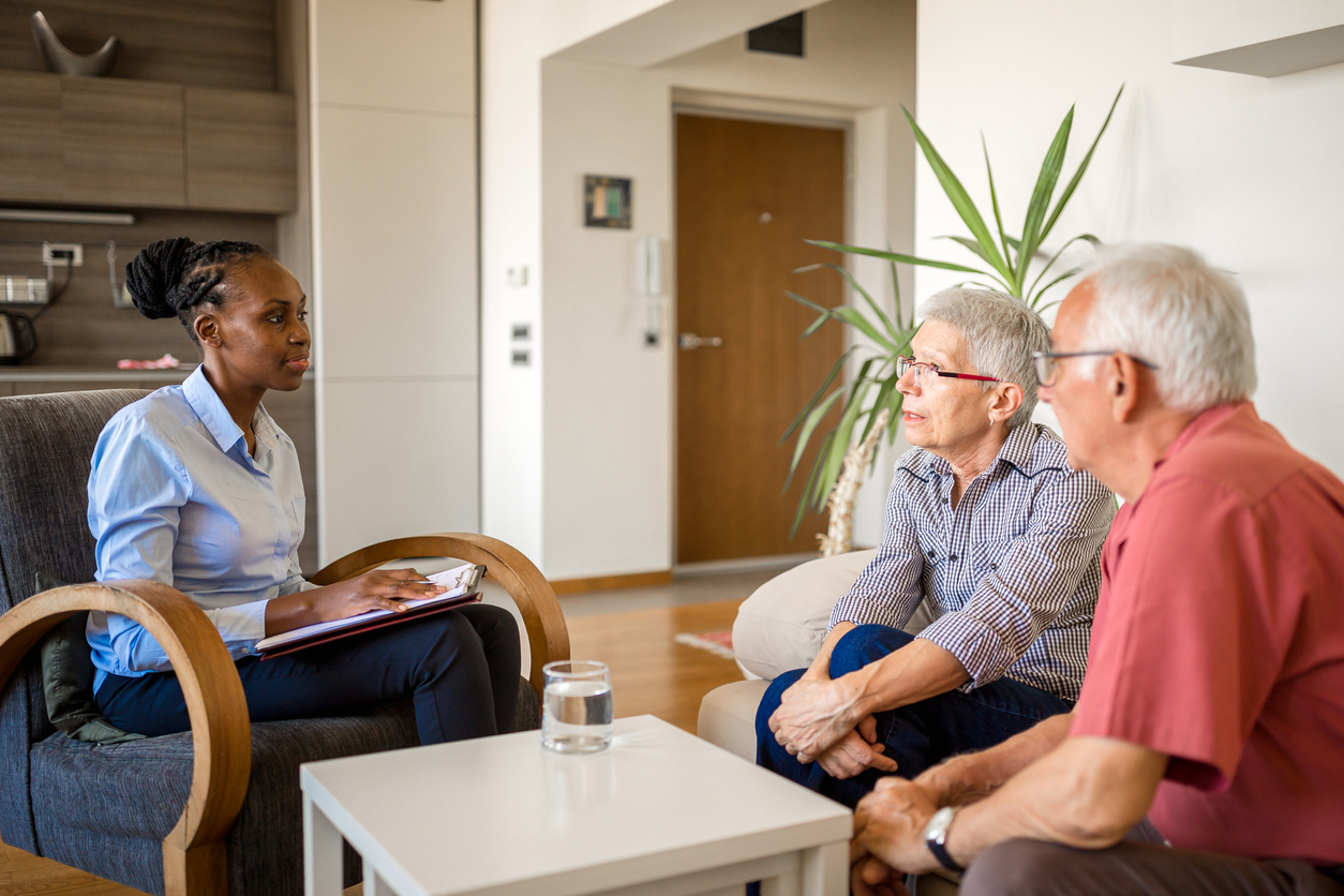 Clinician speaking with elderly clients in an office setting