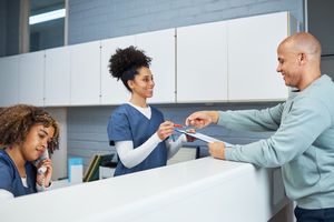 Staff at healthcare facility handing clipboard to a patient